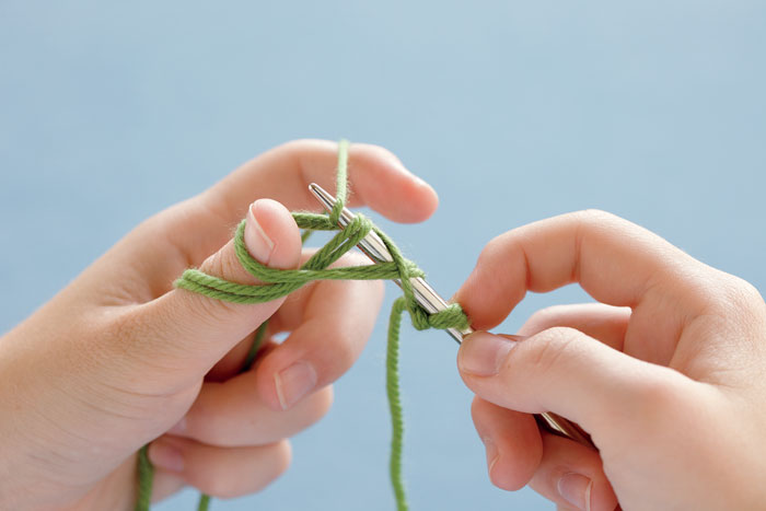 Reach over the top of the single strand and pull a loop through.
